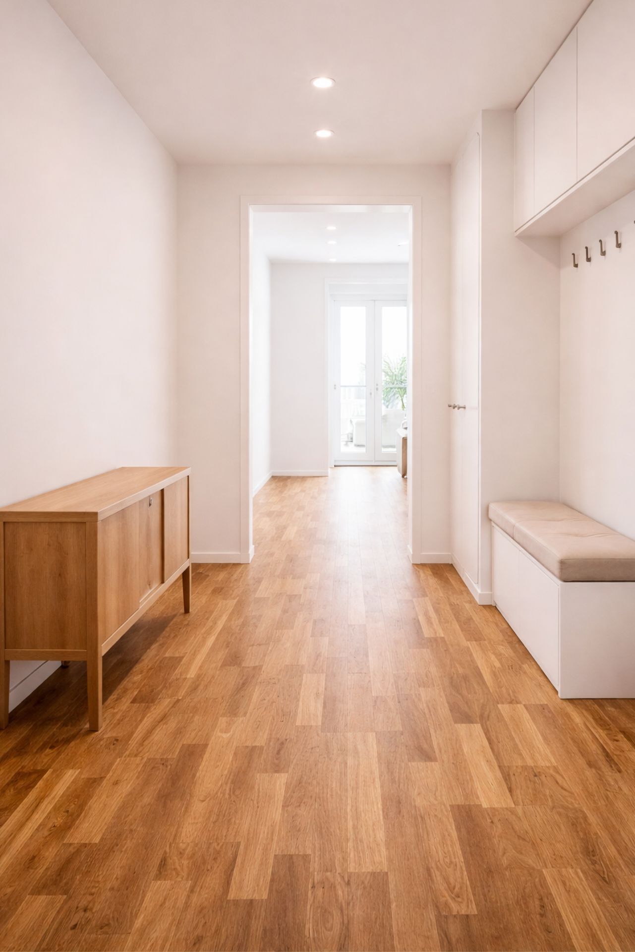 Heller Eingangsbereich mit Holzboden, Sitzbank und Wandgarderobe.